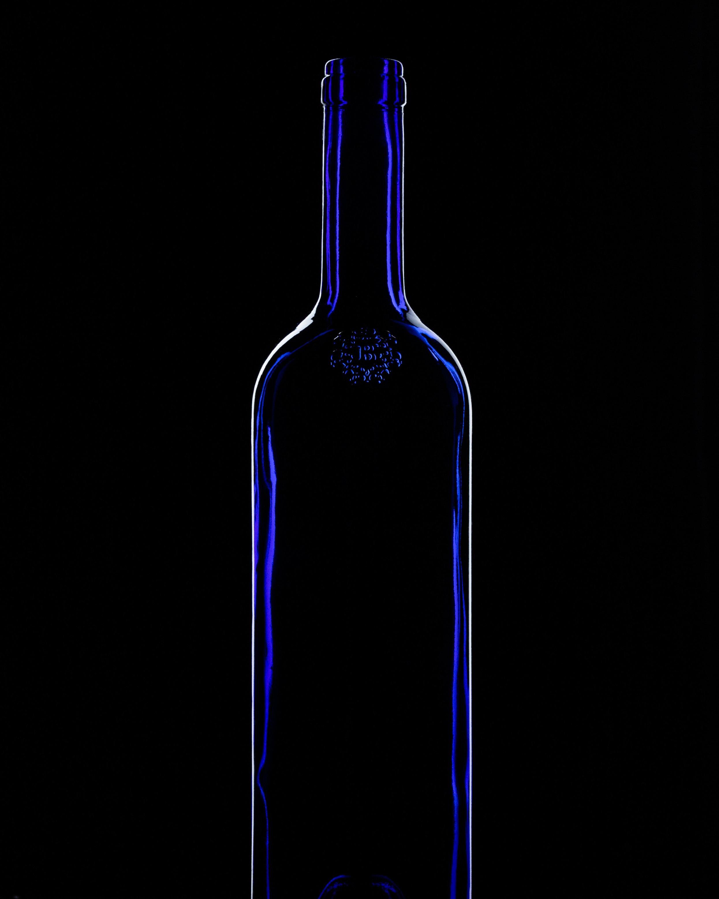 Close up d'une bouteille de vin en verre bleu sur fond noir